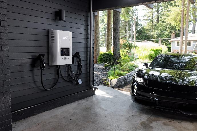 a black car parked in a garage next to an electric charger